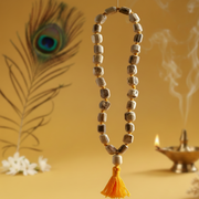 Decorative necklace with tassel on a yellow background with peacock feather and Diwali lamp.