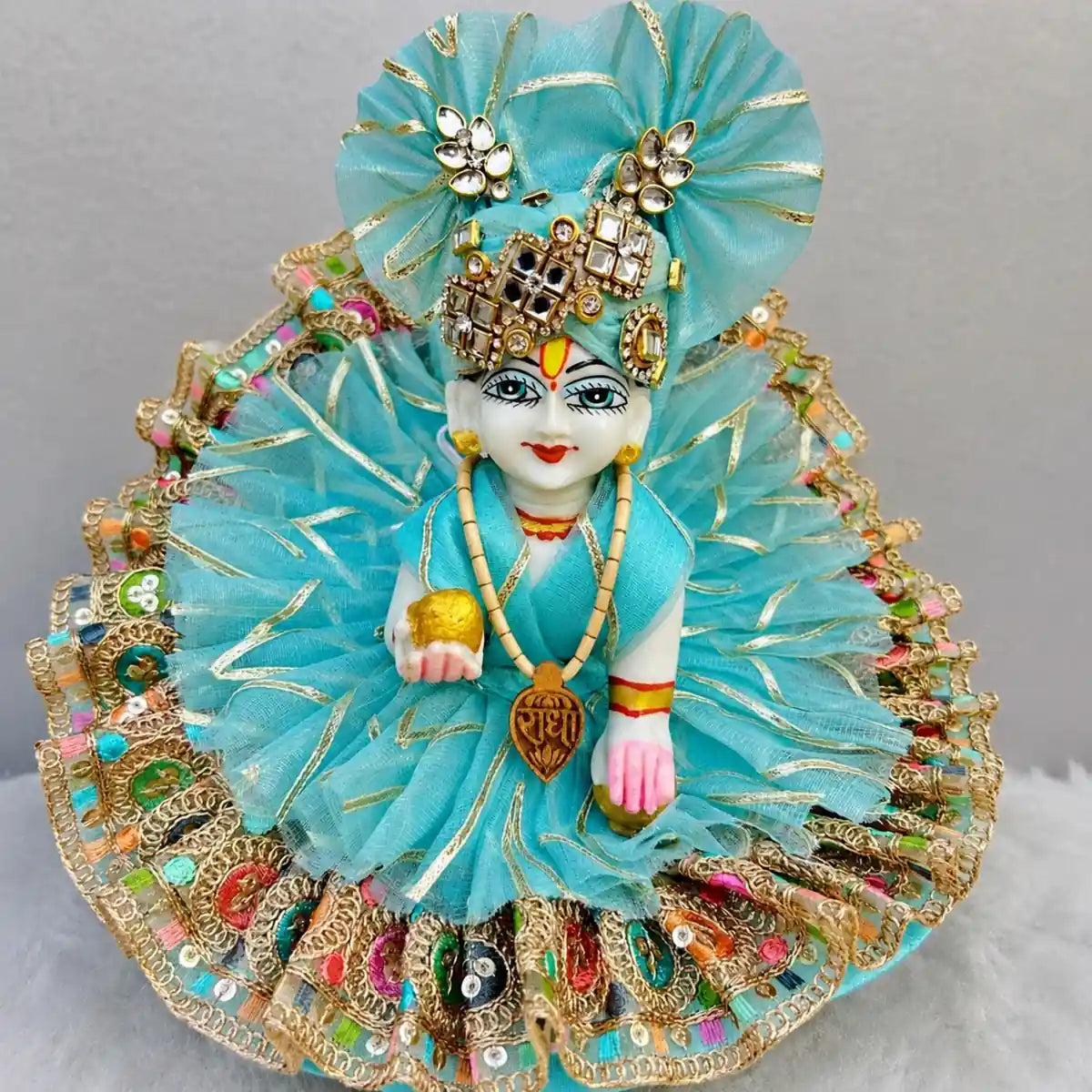 Decorative figure with blue fabric and gold embellishments on a gray background