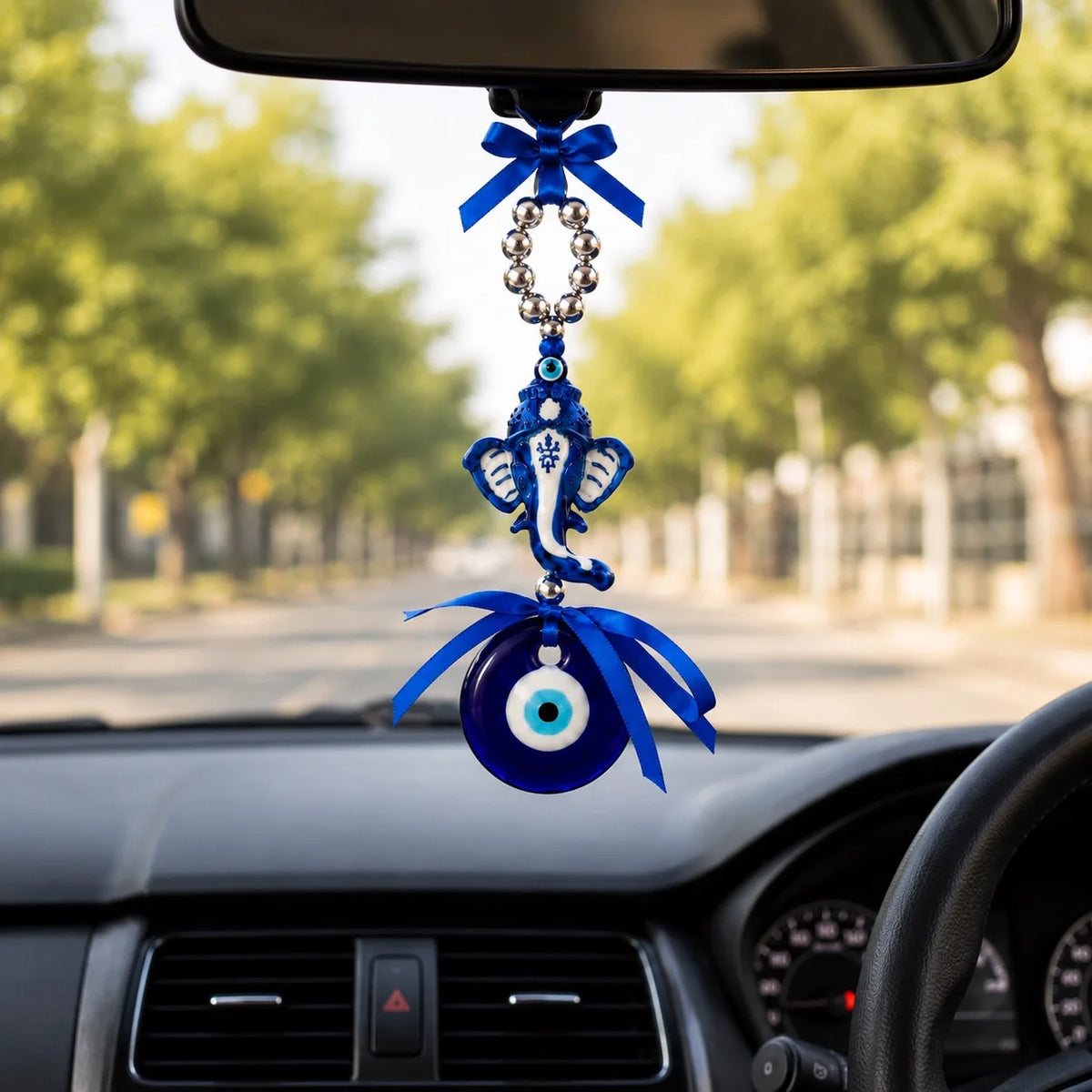 Blue Evil Eye Ganesha charm hanging from car rear-view mirror